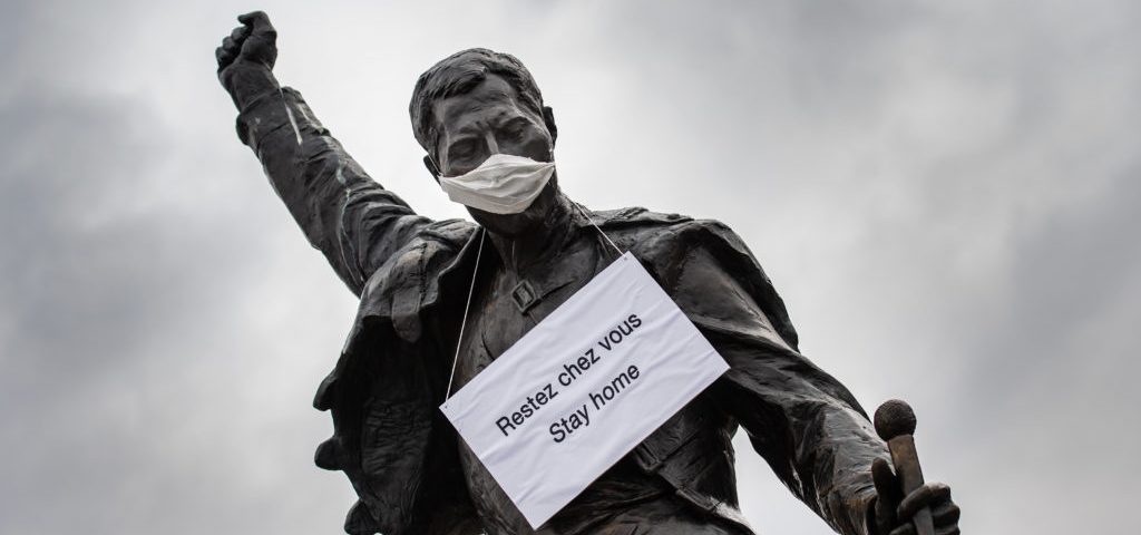 A photograph taken on March 23, 2020 in Montreux shows the statue of Queen's late singer Freddie Mercury wearing a protective facemask and adorned with a placard with a message raising awareness against the spread of the COVID-19 (novel coronavirus), on the shore of the Lake Geneva. - The tribute statue inspired by the cover of Queen's final album "Made in Heaven" was unveiled on November 1996, five years after Mercury a long-time resident of Montreux passed away. (Photo by Fabrice COFFRINI / AFP) (Photo by FABRICE COFFRINI/AFP via Getty Images)